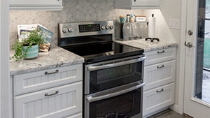 White Cupboards & Hexagon Grey Backsplash on Double Oven Range and Hood