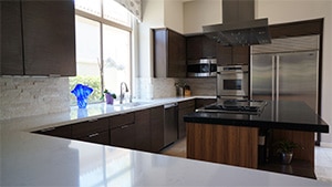 Sober Dark cupboard and White Countertops with refrigerator and double ovens view